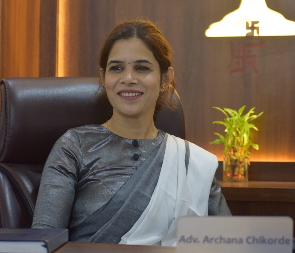 Advocate Archana Chikorde sitting at her desk in her Wakad Pune law office with name plate, providing professional legal consultation with a justice balance symbol in the background